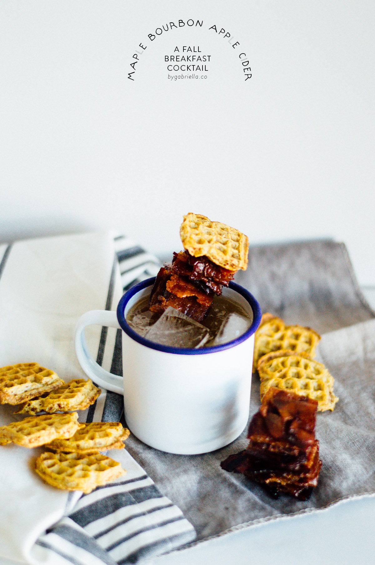 A Maple Bourbon Apple Cider Cocktail recipe with candied bacon and mini waffle toasts! Does it get anymore fall than that? | bygabriella.co