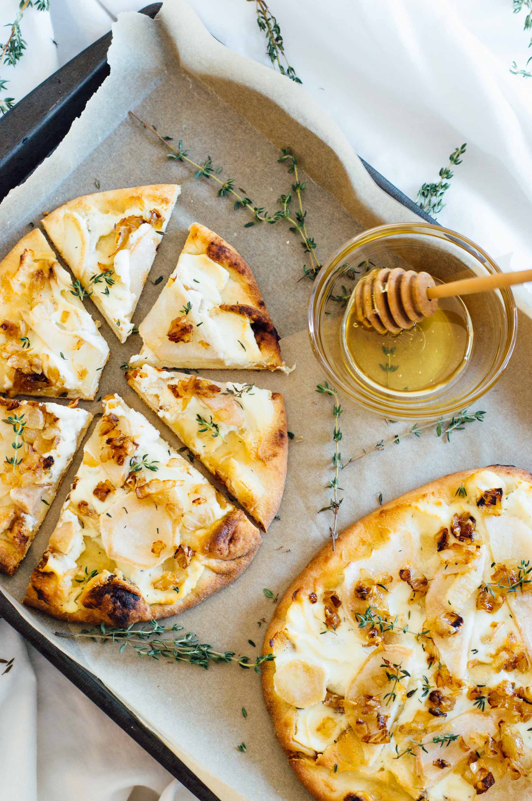 Pear Naan Pizza recipe with Honey Whipped Goat Cheese, fresh thyme and a honey drizzle. | bygabriella.co