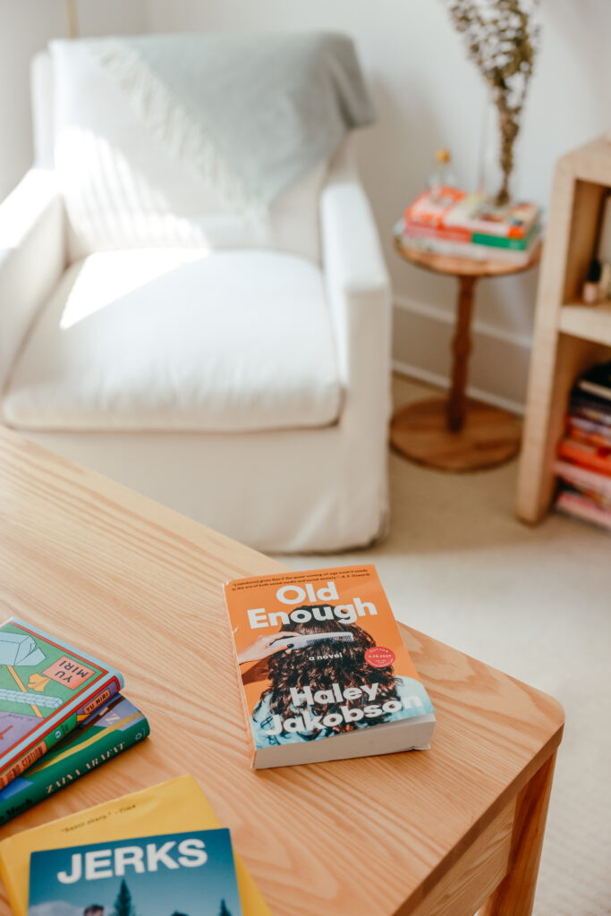 An advanced reader copy of Old Enough appears on a light wood desk with a white swivel armchair in the background